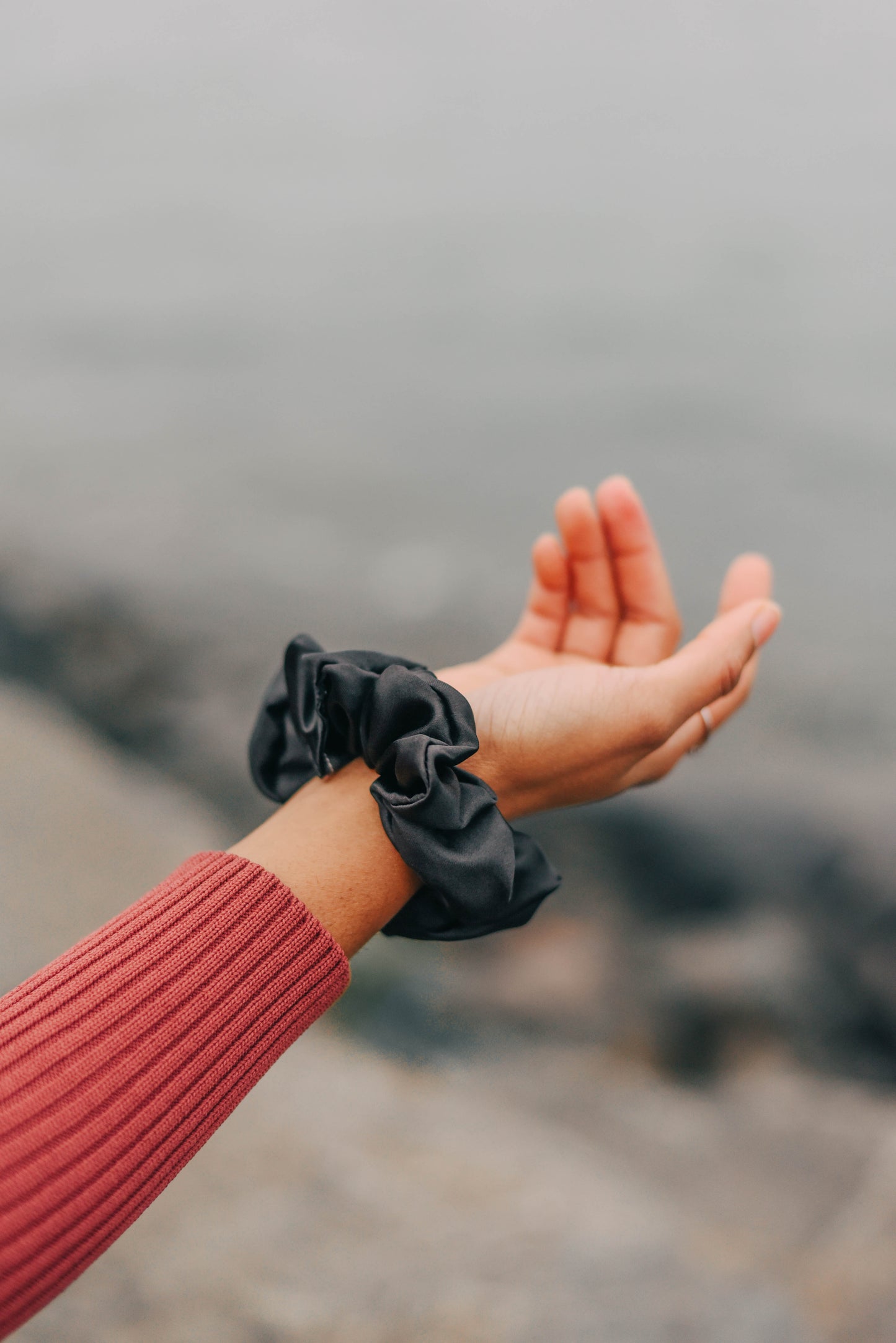 Black coloured aromatic loops scrunchie in hand of model 